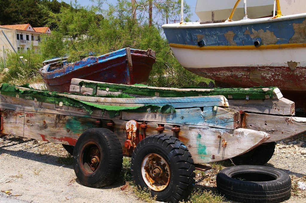 Tandem axle boat trailer parked at a public boat ramp with a fishing boat loaded on bunks