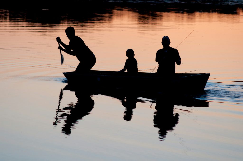 Angler holding a fishing rod on a boat on a calm lake